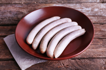 Canvas Print - Cooked sausages on plate on wooden table background