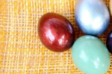 Wall Mural - Colorful easter eggs on bamboo weave sheet background.