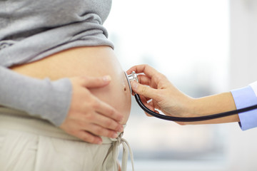 Canvas Print - close up of pregnant woman belly and doctor hand