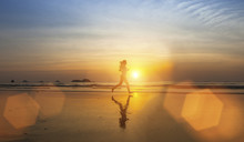 Young Girl Silhouette Jogging On Sea Beach .