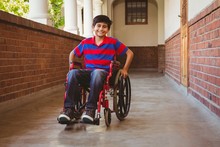 Boy Sitting In Wheelchair In School Corridor