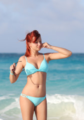 The redhead happy young woman standing at the ocean shore