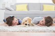 © WavebreakMediaMicro - Siblings sleeping with dog on rug