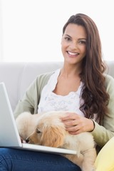 Sticker - Happy woman with dog using laptop on sofa