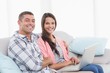 © WavebreakmediaMicro - Happy couple with laptop sitting on sofa