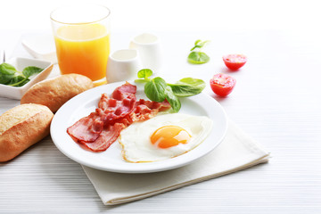 Bacon and eggs on color wooden table and white background