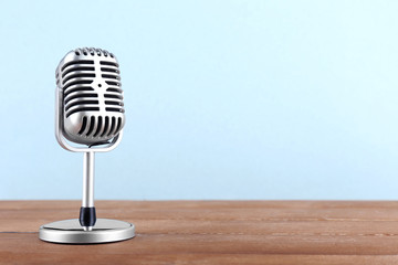 Wall Mural - Retro microphone on wooden table on light background