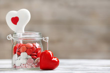 Sweet Candies In Glass Jar With Hearts On Wooden Background