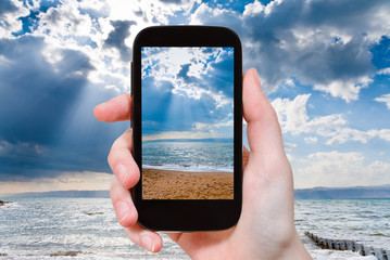 Canvas Print - tourist taking photo of sunbeams over Dead Sea