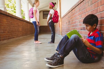 Wall Mural - Schoolboy with friends in background at school corridor