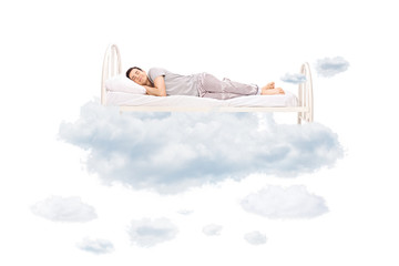 Wall Mural - Young man sleeping on a comfortable bed in clouds