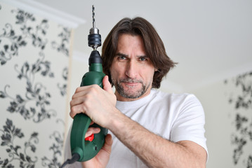 middle-aged man with a drill in  hands of