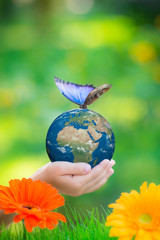 Canvas Print - Child holding Earth planet with blue butterfly in hands