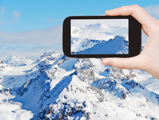 Sticker - tourist taking photo of snow mountains in Alpes