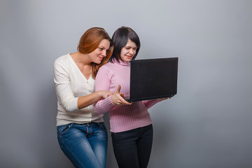 two girls European appearance blonde and brunette in a computer