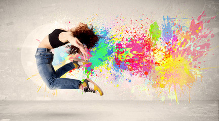 Wall Mural - Happy teenager jumping with colorful ink splatter on urban backg