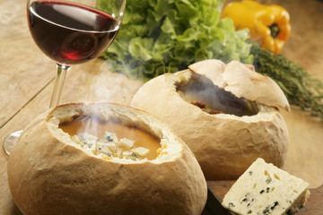 Hot vegetable soup served in bread with a glass of red wine