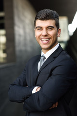 Wall Mural - Young businessman near a office building wearing black suit