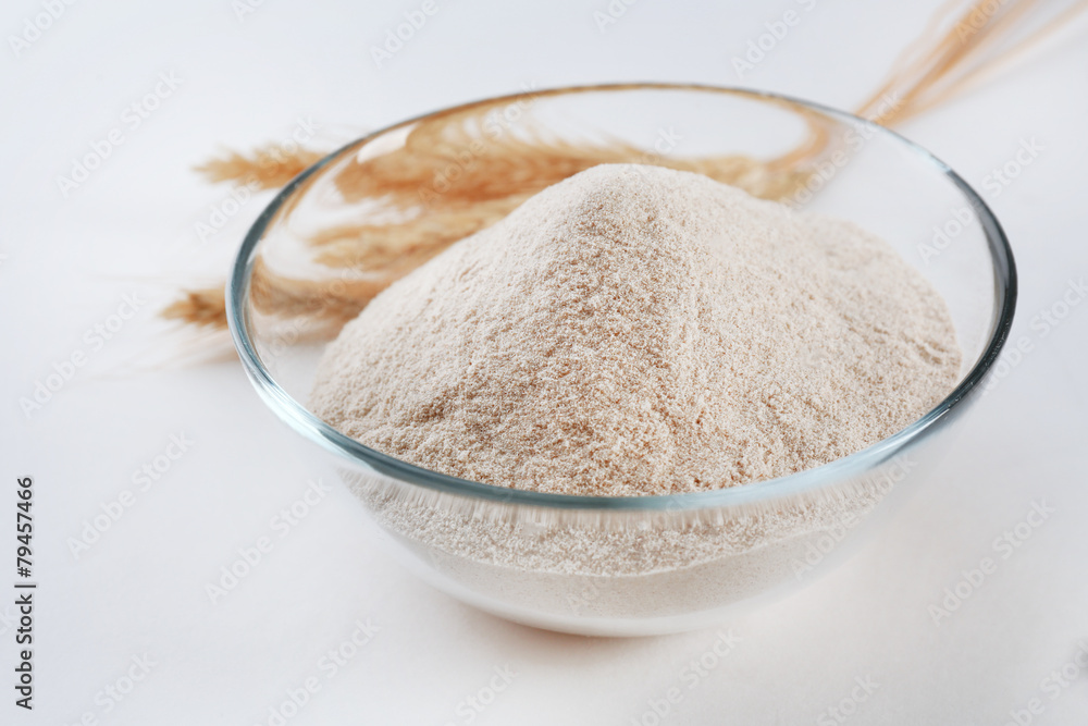 Glass bowl with flour and ears isolated on white
