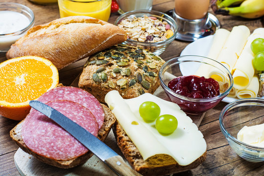 Fototapete - gedeckter Frühstückstisch mit Brötchen, Käse, Obst und Marmelade