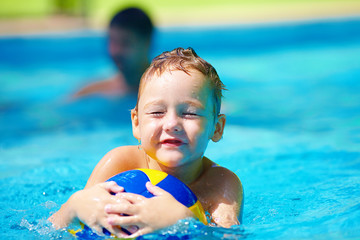 Wall Mural - cute kid playing water sport games in pool