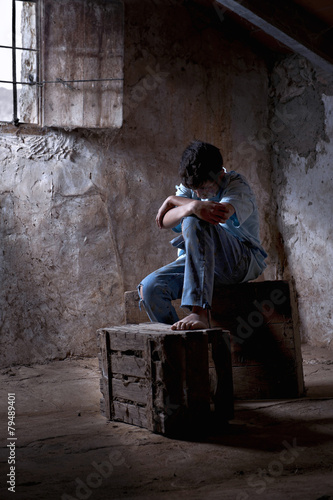 Fotografia, Obraz Young man, 12 years, dirty, mistreaded, sat in a garret