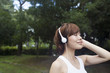 © Mint Images - A woman in a Kyoto park, wearing headphones. Wearing jogging kit.