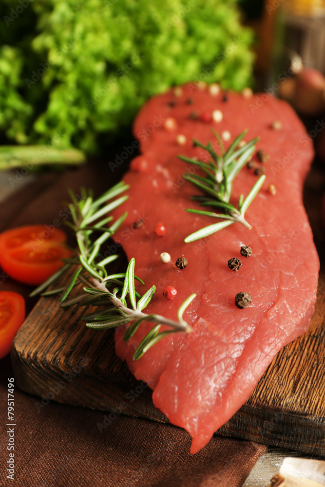 Raw beef steak with spices and greens on table close up