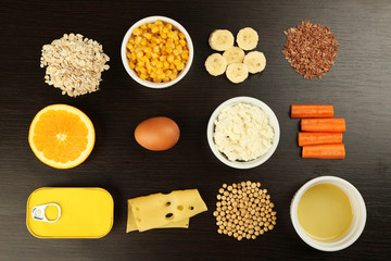 Various food products containing vitamins on wooden background