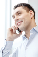 Wall Mural - smiling businessman with smartphone in office