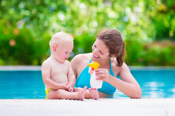 Wall Mural - Mother applying sun screen on baby in swimming pool