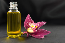 Aromatic Massage Oil And Orchid Flower On Dark Background