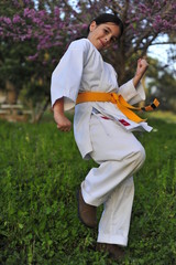 Wall Mural - Young girl in kimono w yellow belt exercising karate.