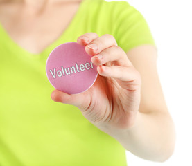 Wall Mural - Round volunteer button in hand of girl isolated on white