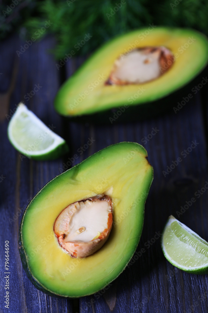 Sliced avocado with lime and herb on wooden table, closeup