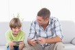 © WavebreakMediaMicro - Father and son playing games on cell phone