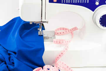 Sewing machine, fabric draped and centimeter on a white backgrou