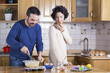 Man whisking dough and woman eating homemade cupcakes