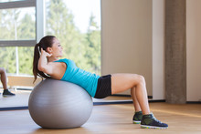 Smiling Woman With Fit Ball Flexing Muscles In Gym