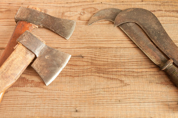 Two dated and used cleavers and billhooks on wooden background