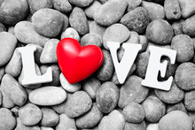 The Word Love With Red Heart On Pebble Stones