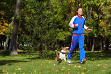 Young Attractive Sport Girl Jogging With Dog In Sunny Park