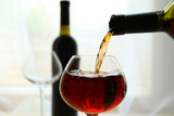 Fototapeta Storczyk - Red wine pouring into wine glass, close-up