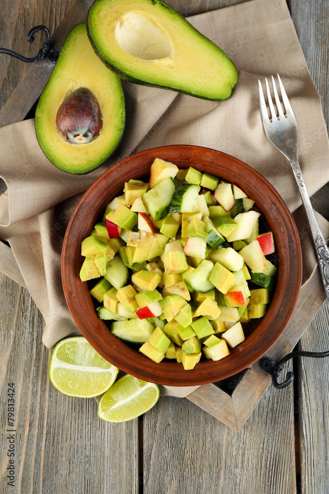 Salad with apple and avocado in bowl on tray on table close up