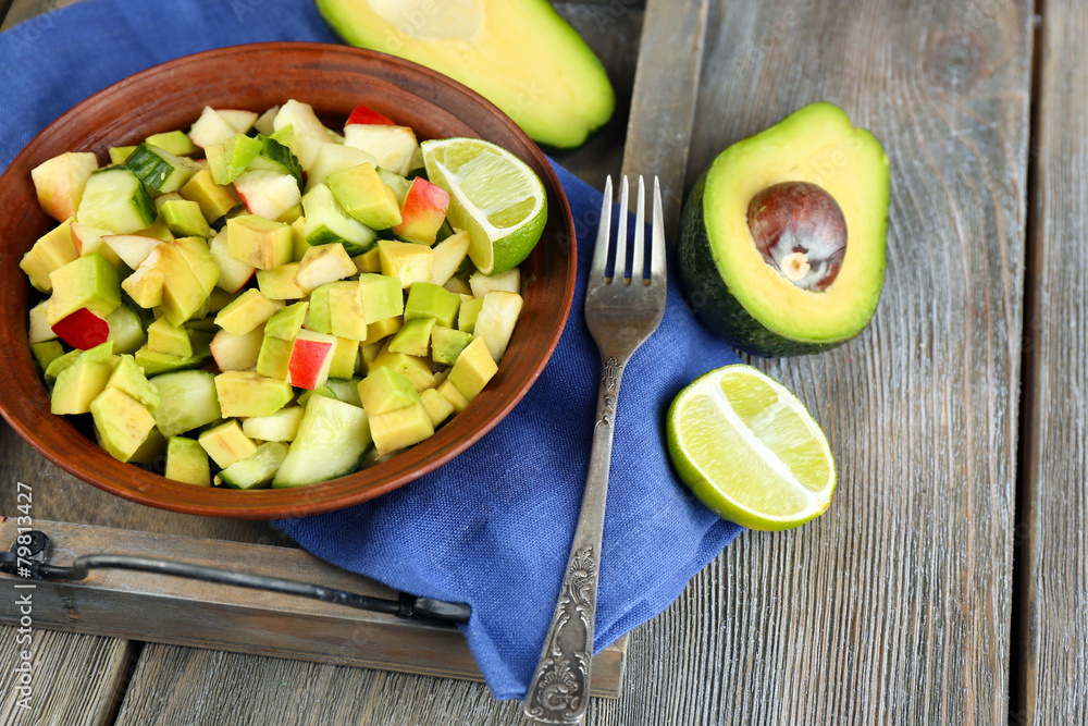 Salad with apple and avocado in bowl on tray on table close up