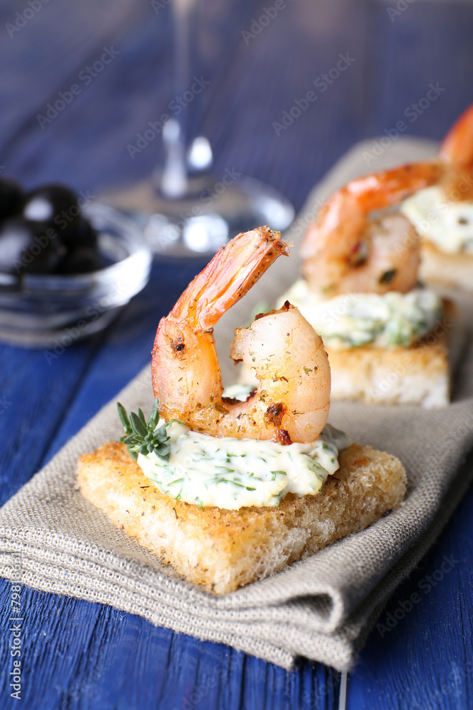 Appetizer canape with shrimp on napkin on table close up