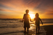 © Creativa Images - Two children holding hands at beach