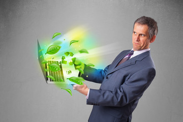 Wall Mural - Businessman holding laptop with recycle and environmental symbo