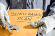 Worker holding a folder of maintenance plan and monkey wrench