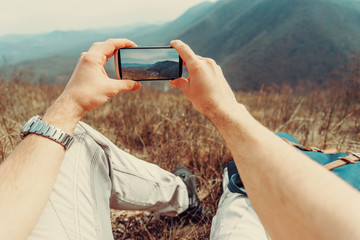 Wall Mural - Man taking photographs mountain with smartphone